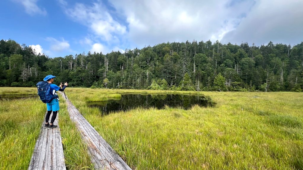 Hiker walking along a wooden trail through the Oze wetland in Japan